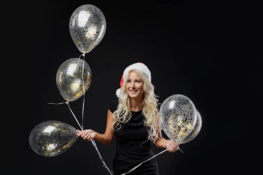 Brightfull ifadeleri Noel Baba şapkası siyah arka plan üzerinde Noel partisi kutluyor mutlu duygular kız portresi. Bir bardak şampanya ve altın balon tutar. Yeni yıl tatil kavramı