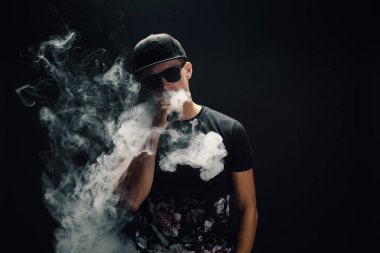 Vape adam. Bir modern siyah kap vaping ve Elektronik Sigara Buhar puffs kapalı icar yakışıklı genç bir beyaz adam portresi