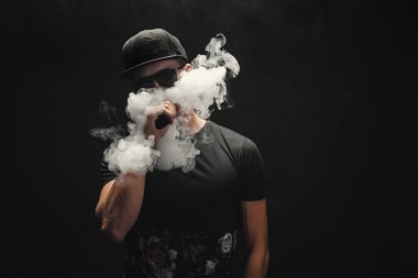 Vape adam. Bir modern siyah kap vaping ve Elektronik Sigara Buhar puffs kapalı icar yakışıklı genç bir beyaz adam portresi
