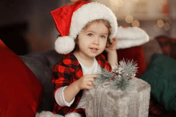 圣诞可爱的幼儿女孩在圣诞老人的帽子拿着一个礼品盒 家庭度假的概念 — 图库照片