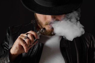 Adam vaping mod Buhar siyah stüdyo arka plan adlı parçasıyla birlikte kullanılmalıdır. Sakallı adam e-sigara tütün çıkmak için. Buharı ve alternatif nikotin ücretsiz sigara kavramı, portre