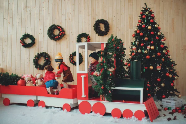 Szczęśliwe Dzieci Siedzi Boże Narodzenie Drewniany Pociąg Ozdobione Choinki Oddziałów — Zdjęcie stockowe