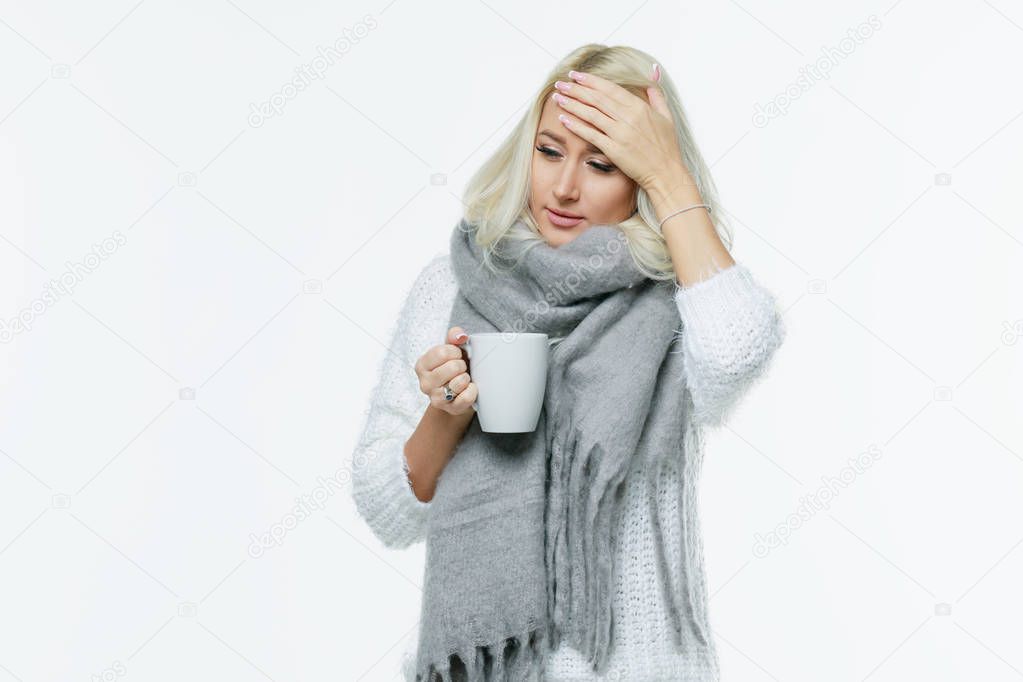 Sickness cute young blonde woman wrapped scarf having headache, touching her temple and closed eyes, closeup. Cold, virus, migraine, flu season concept.