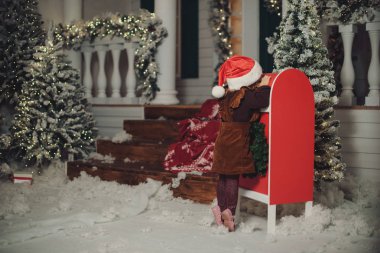 Küçük bir kız bebek beyaz örgü şapkalı bir dilek yapar ve Noel Baba'ya bir mektup yazar ve bir kartpostal posta ile gönderir. Posta kutusunda zarf atar