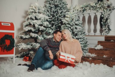 şık mutlu çift büyük kırmızı ile yavaşça Noel ışıkları sarılma gülümsüyor mevcut. kış tatil günlerinde rahat sundurma, mevsimlik selamlar neşeli rahat anlar. reklam kavramı. 