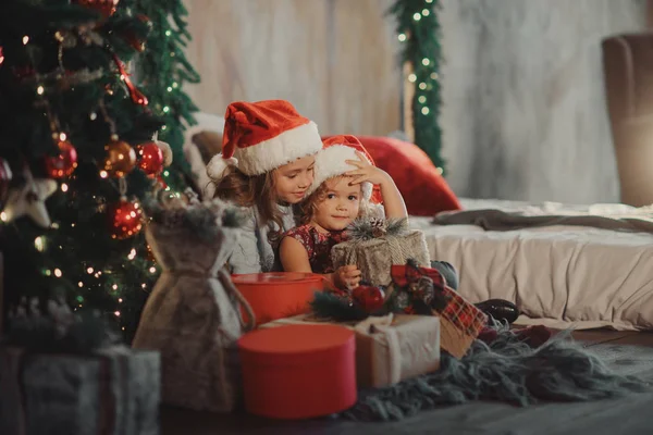 Mutlu Noeller ve mutlu tatil! İki sevimli küçük çocuk kızlar kız Noel sihirli hediye kutusu açın. Yeni yıl dekorasyon ve Noel ağacı ile rahat oda 
