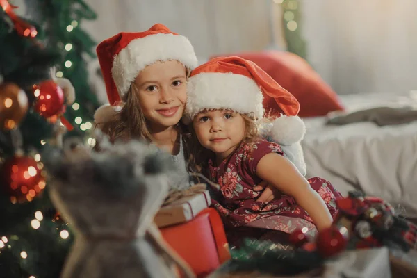 圣诞快乐 节日快乐 两个可爱的小女孩姐妹打开神奇的礼品盒在圣诞节 舒适的房间 新年装饰和圣诞树 — 图库照片