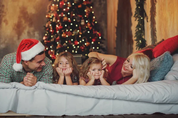 圣诞快乐 节日快乐 愉快的父母和两个小孩在客厅的床上的圣诞树附近玩耍和玩耍 — 图库照片
