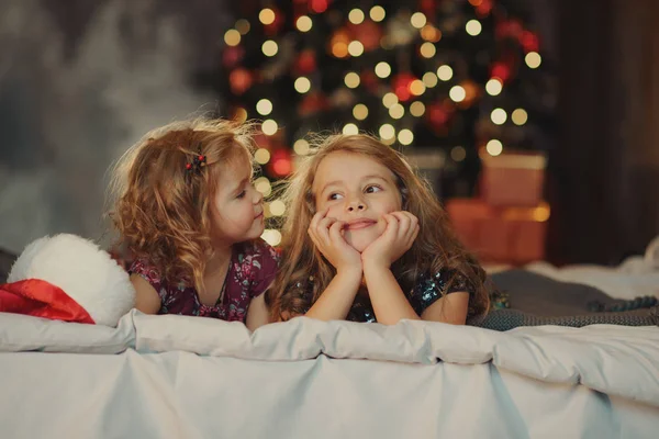 Vor Dem Hintergrund Eines Festlichen Weihnachtsbaums Sitzen Zwei Süße Schwestern — Stockfoto