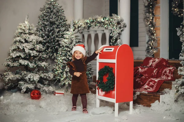 Küçük bir kız bebek beyaz örgü şapkalı bir dilek yapar ve Noel Baba'ya bir mektup yazar ve bir kartpostal posta ile gönderir. Posta kutusunda zarf atar