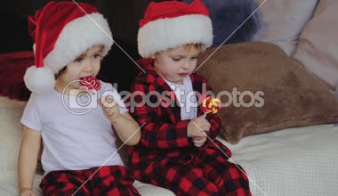 Noel Baba şapkaları Noel ağacının altına oturma odasında oturup, küçük çocuklar ve kız ve açık sunar ve şeker yiyor. Aile kavramı