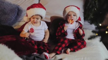 Noel Baba şapkaları Noel ağacının altına oturma odasında oturup, küçük çocuklar ve kız ve açık sunar ve şeker yiyor. Aile kavramı