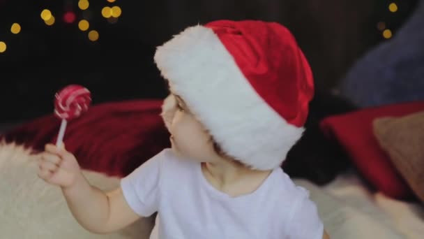 孩子在圣诞老人服装吃甜糖果在一根棍子 有乐趣在圣诞节的时候 圣诞快乐概念 — 图库视频影像
