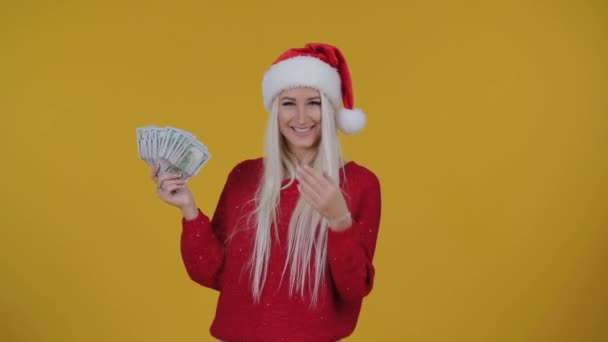 快乐的金发碧眼的女人在红色圣诞老人帽子拿金钱钞票在黄色背景 在彩票中赢得现金 新年假期2019年概念 — 图库视频影像