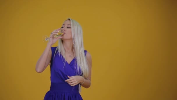 在黑色星期五购物时 金发碧眼的女人穿着蓝色豪华礼服 带着一杯香槟酒 复制销售广告的空间 黄色背景 无彩提党 — 图库视频影像