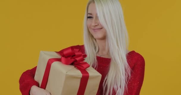 幸せな興奮した若い金髪女性は 黄色の背景の上に赤いリボン ボックスの贈り物を与えます すごい驚きの効果 — ストック動画