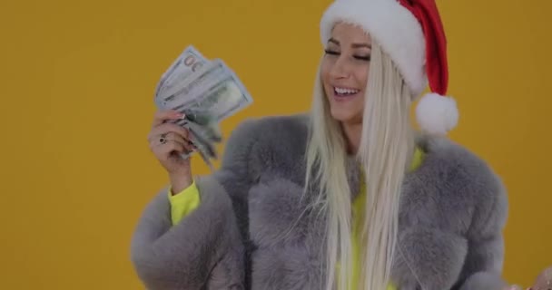 在圣诞老人帽子和毛皮外套的妇女得到鞋子和现金作为礼物或她的购物的喜悦 惊讶和高兴地收到高跟鞋作为礼物 在黄色背景 — 图库视频影像
