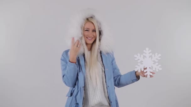 ホワイト スタジオの背景で毛皮のコートで金髪の若い女性 雪の結晶の置物を保持 — ストック動画