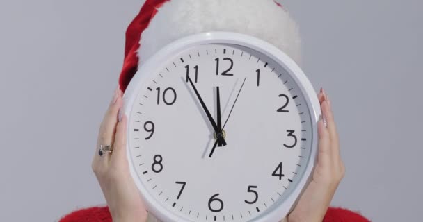 新年后期和圣诞购物女孩与大挂钟在圣诞老人克劳斯帽子在白色工作室背景 — 图库视频影像