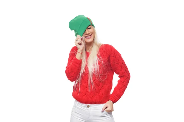 明るいを着てファッション金髪女性ニット緑の帽子と赤いセーターの分離の白い背景の上楽しんで — ストック写真