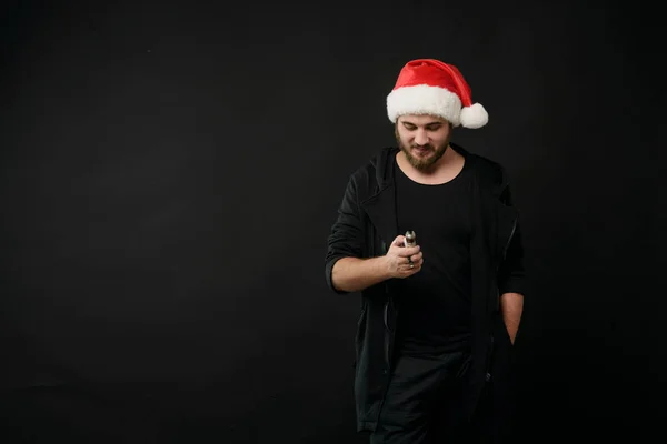 Man with beard in Santa red hat smoking electronic sigarette. vape pen. vape smoke. Christmas concept