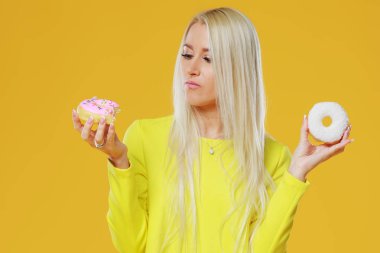 İki donut sprinkles üzerinde sarı bir arka plan ile arasında kadın seçme. Yemek ve lezzetli kavramı