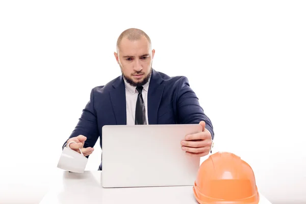 一个穿着橙色头盔的疲惫的建筑工人商人看着笔记本电脑屏幕 研究建设项目 坐在桌旁喝咖啡 — 图库照片