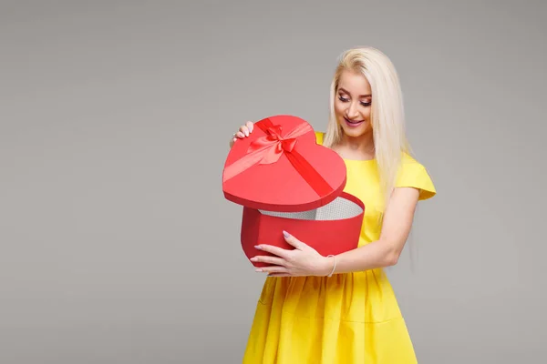 バレンタイン デイのハート ボックスと灰色の背景に黄色のドレスでブロンドの女の子 コピーのテキストのための領域 — ストック写真