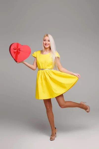 バレンタイン デイのハート ボックスと灰色の背景に黄色のドレスでブロンドの女の子 コピーのテキストのための領域 — ストック写真
