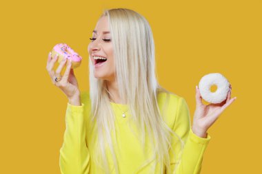 İki donut sprinkles üzerinde sarı bir arka plan ile arasında kadın seçme. Yemek ve lezzetli kavramı