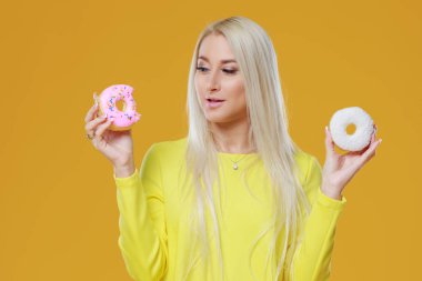 İki donut sprinkles üzerinde sarı bir arka plan ile arasında kadın seçme. Yemek ve lezzetli kavramı