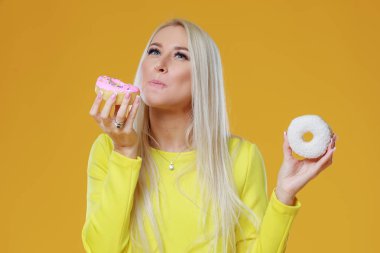 İki donut sprinkles üzerinde sarı bir arka plan ile arasında kadın seçme. Yemek ve lezzetli kavramı
