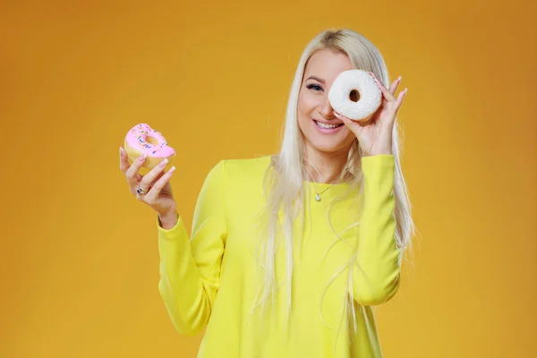 Woman Choosing between two donuts with sprinkles on a yellow background. Concept of food and Tasty