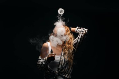 Kızıl saçlı kadın vaping elektronik sigara duman siyah arka plan ile. Genç kadın e-sigara tütün çıkmak için. Buharı ve alternatif nikotin ücretsiz Sigara kavramı kopya alanı 
