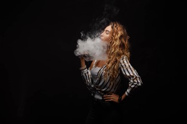 Kızıl saçlı kadın vaping elektronik sigara duman siyah arka plan ile. Genç kadın e-sigara tütün çıkmak için. Buharı ve alternatif nikotin ücretsiz Sigara kavramı kopya alanı 