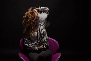 Kızıl saçlı kadın vaping elektronik sigara duman siyah arka plan ile. Genç kadın e-sigara tütün çıkmak için. Buharı ve alternatif nikotin ücretsiz Sigara kavramı kopya alanı 