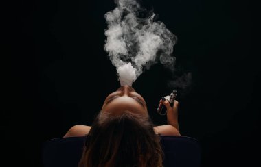 Kızıl saçlı kadın vaping elektronik sigara duman siyah arka plan ile. Genç kadın e-sigara tütün çıkmak için. Buharı ve alternatif nikotin ücretsiz Sigara kavramı kopya alanı 