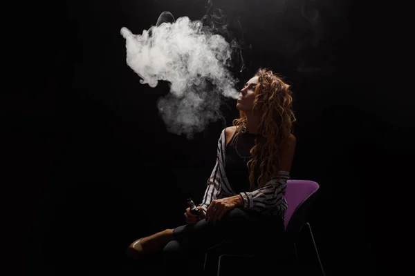 Kızıl saçlı kadın vaping elektronik sigara duman siyah arka plan ile. Genç kadın e-sigara tütün çıkmak için. Buharı ve alternatif nikotin ücretsiz Sigara kavramı kopya alanı 
