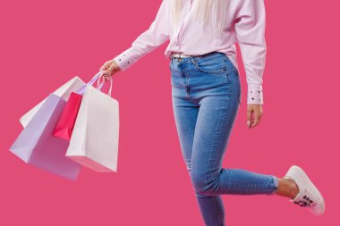 Bir alışveriş torbaları pembe arka plan üzerinde tutan eller
