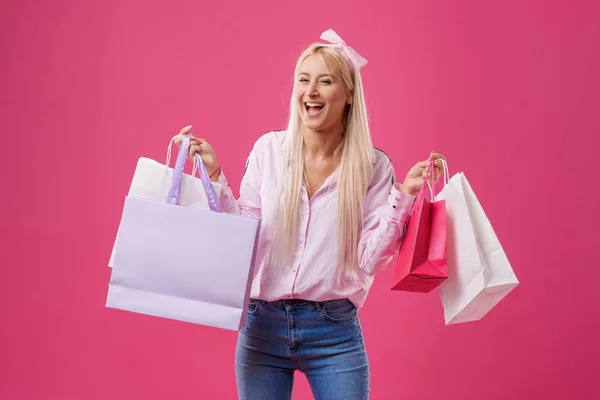 消費者や販売人のコンセプト 微笑む若い金髪の女性の買い物袋とピンクの背景 — ストック写真