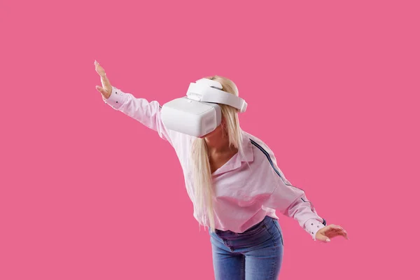 年轻金发快乐的女学生与虚拟现实护目镜 工作室拍摄的粉红色的背景 虚拟学习 — 图库照片