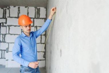 Memnun inşaat işçisi foreman bir mezura yapım aşamasında bir evde bir duvar parametrenin ölçer. Onarım hazırlık ve gerçekleşen çalışma doğruluğunu inceler