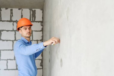 Memnun inşaat işçisi foreman bir mezura yapım aşamasında bir evde bir duvar parametrenin ölçer. Onarım hazırlık ve gerçekleşen çalışma doğruluğunu inceler