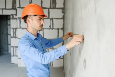 Memnun inşaat işçisi foreman bir mezura yapım aşamasında bir evde bir duvar parametrenin ölçer. Onarım hazırlık ve gerçekleşen çalışma doğruluğunu inceler