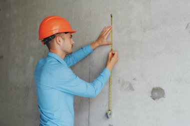 Memnun inşaat işçisi foreman bir mezura yapım aşamasında bir evde bir duvar parametrenin ölçer. Onarım hazırlık ve gerçekleşen çalışma doğruluğunu inceler