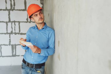 Defter üzerinde inşaat danışman yazar duvara yakın. Yakışıklı Foreman'ın içinde clipboard not alma. İnşaat Müfettiş denetimi yeni nesne