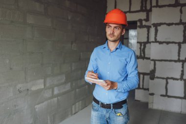 Defter üzerinde inşaat danışman yazar duvara yakın. Yakışıklı Foreman'ın içinde clipboard not alma. İnşaat Müfettiş denetimi yeni nesne