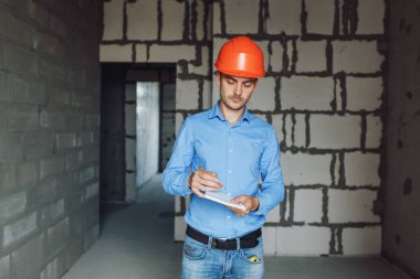 Defter üzerinde inşaat danışman yazar duvara yakın. Yakışıklı Foreman'ın içinde clipboard not alma. İnşaat Müfettiş denetimi yeni nesne