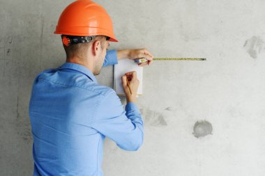 Defter üzerinde inşaat danışman yazar duvara yakın. Yakışıklı Foreman'ın içinde clipboard not alma. İnşaat Müfettiş denetimi yeni nesne