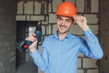 Adam koruyucu miğfer elektrikli matkap ile gülümseyen. Onarım kavramı